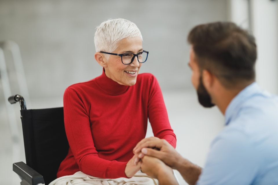A caregiver sharing a warm conversation with a smiling senior woman