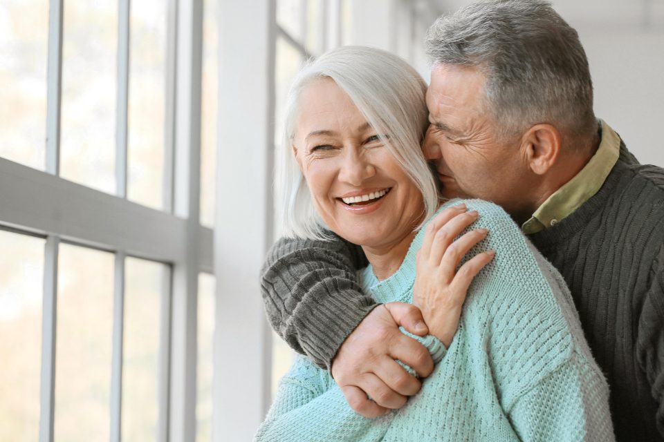 A joyful senior couple embracing by a bright window